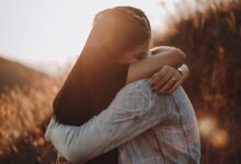 woman in black long sleeve shirt and blue denim jeans covering her face with her hand