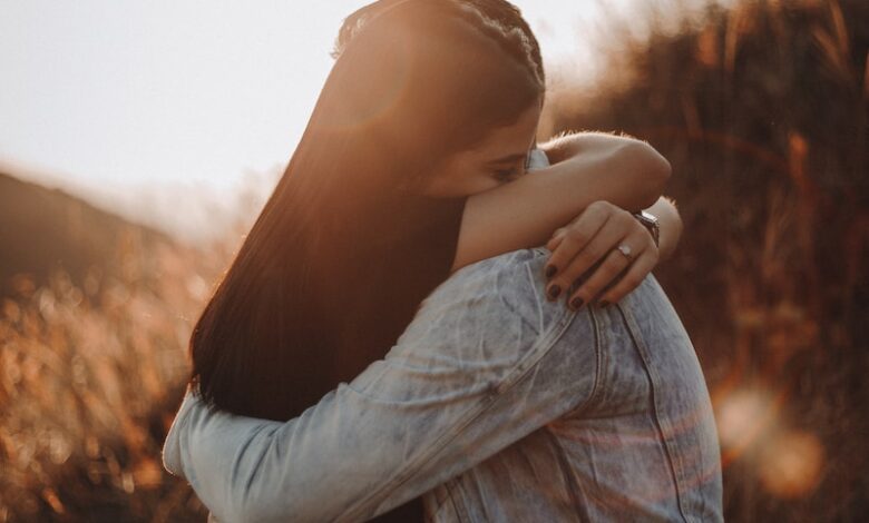 woman in black long sleeve shirt and blue denim jeans covering her face with her hand